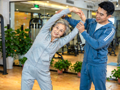 老年人在教练陪伴下进行温和的伸展运动